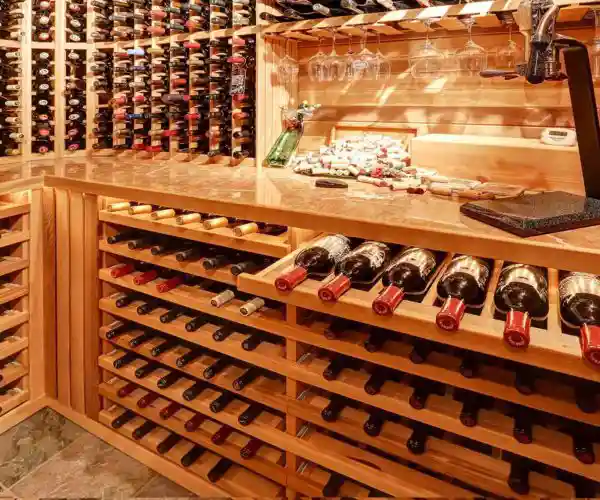 Cave à vin en bois du restaurant bordelais la table de trois avec de nombreuses bouteilles soigneusement rangées sur des étagères.